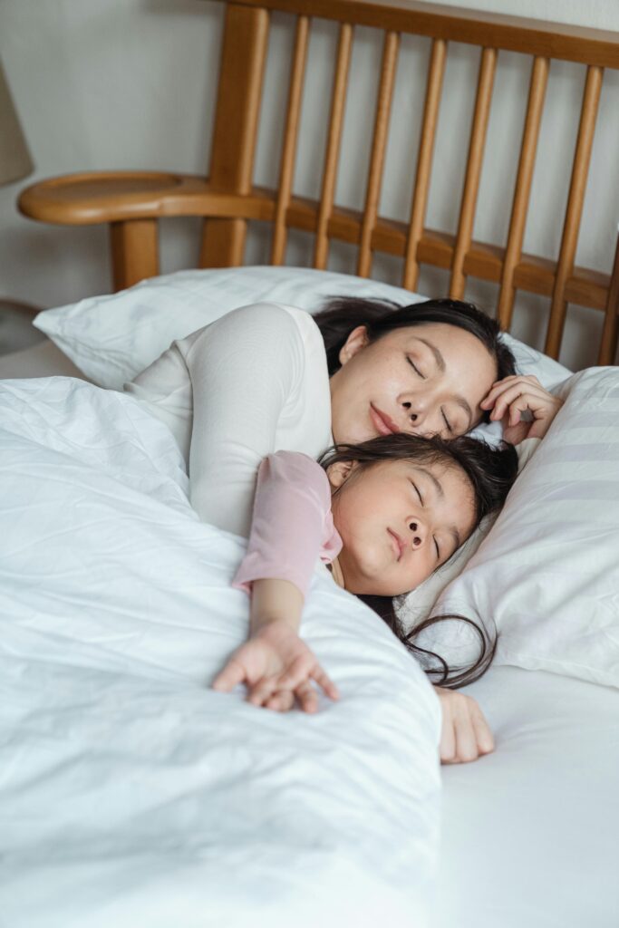 A serene moment capturing a mother and daughter cuddling in bed, enjoying restful sleep.