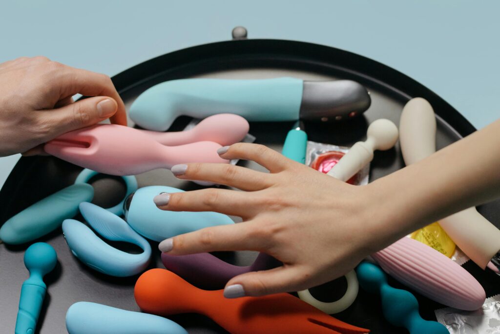 An assortment of vibrant sex toys with hands reaching for selection.